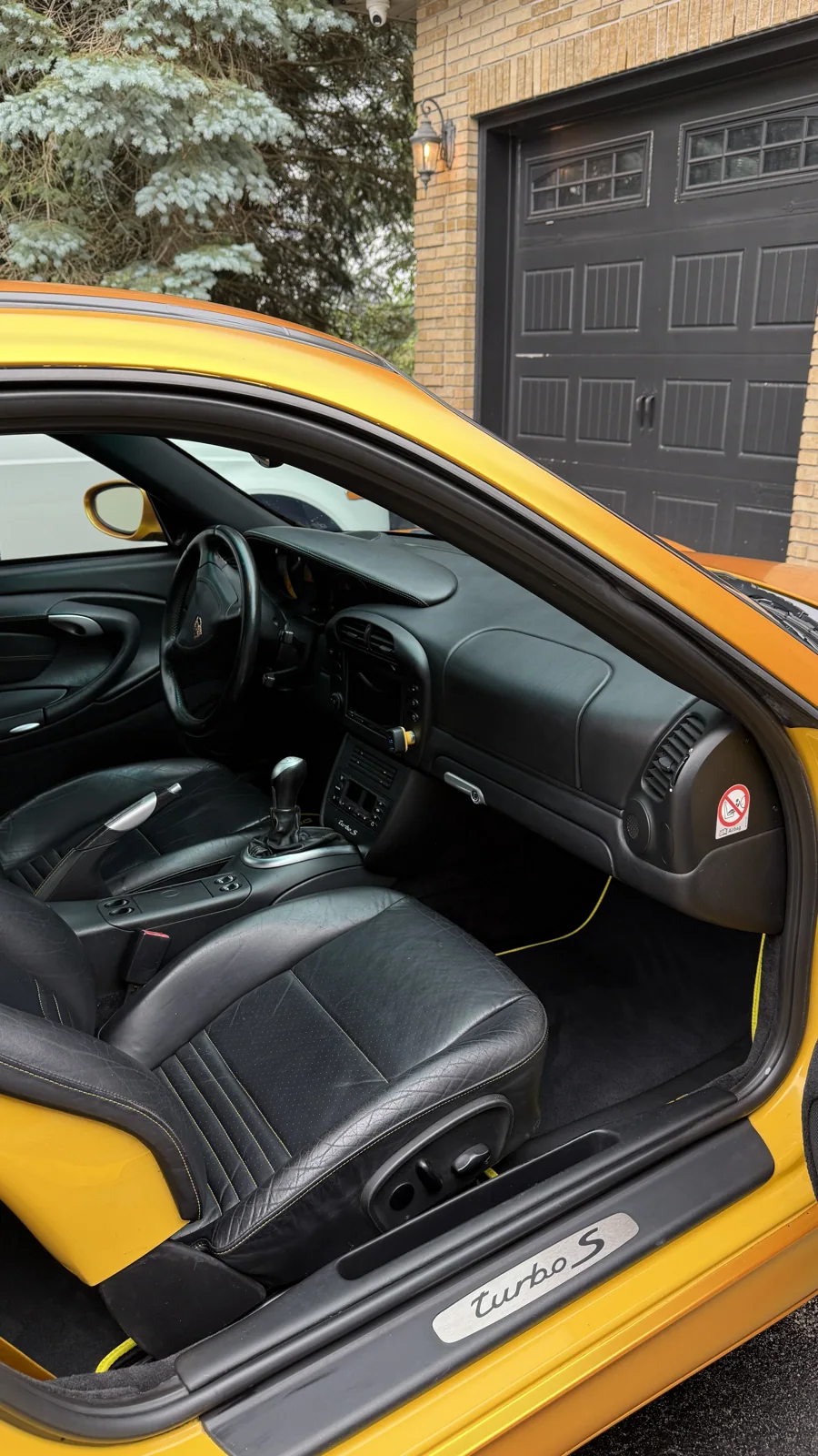 Detailed black leather interior of a yellow Porsche